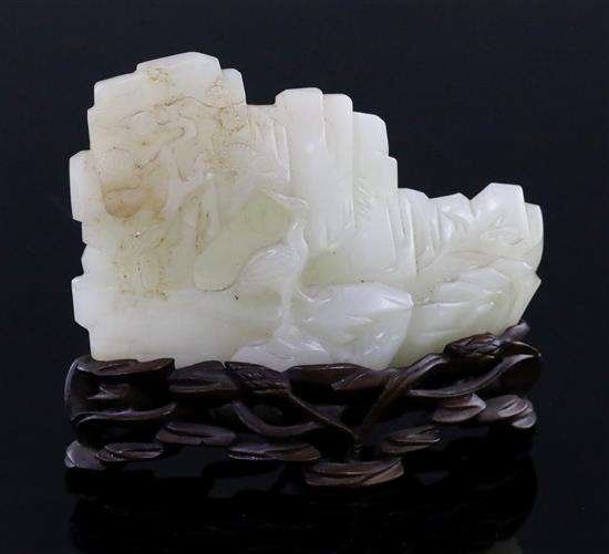 A Chinese pale celadon jade landscape carving, 19th century, W. 9cm, H. 6cm, millet and rockwork carved wood stand